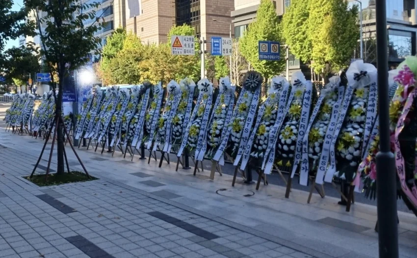 Funeral flowers have become a symbol of protests among Korean fans, used to express strong disapproval. Recent incidents involved protests against Seunghan’s return to RIIZE and Suga’s DUI case, with fans sending funeral wreaths to demand their removal.